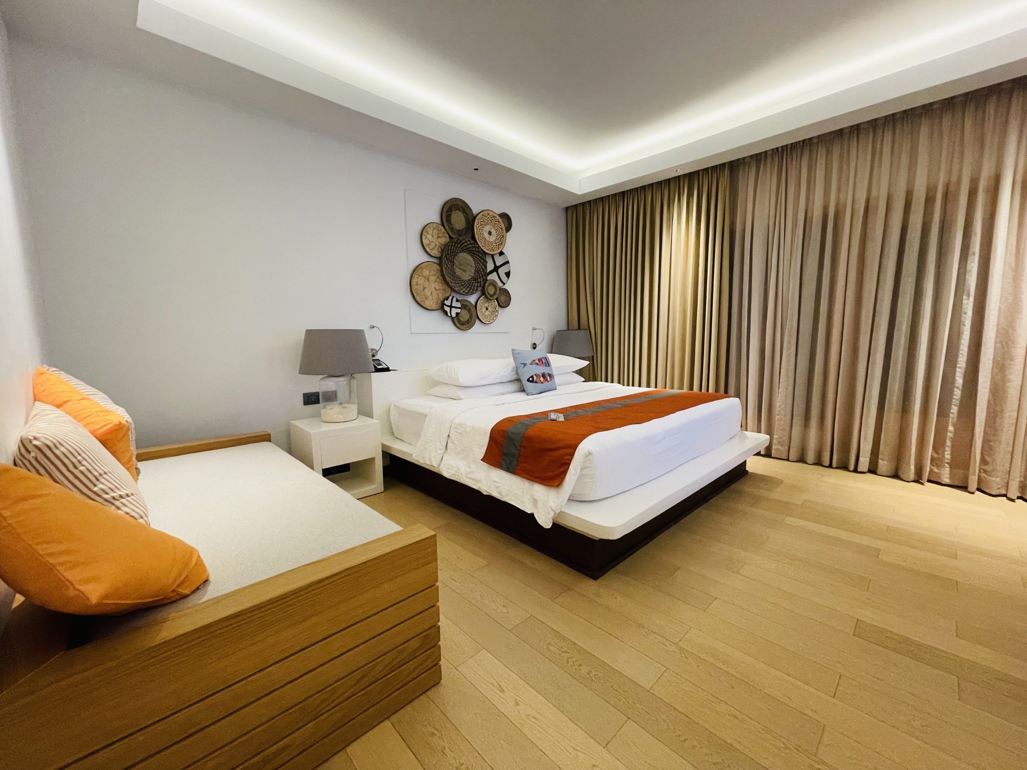 Guest room with a freshly made bed in white linens and a tidy seating bench